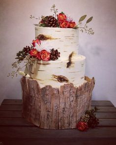 a three tiered cake decorated with flowers and pine cones