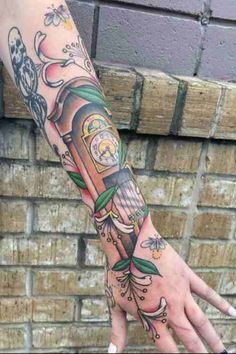 a person's arm with tattoos on it and a clock in the middle of their arm