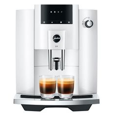 a coffee machine with two glasses next to it on a white surface and black trim around the edges