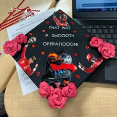 a decorated graduation cap sitting on top of a laptop computer next to flowers and paper