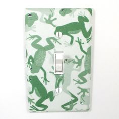 a light switch cover with green frogs on it