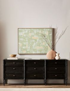 a black dresser with two vases and a painting on the wall