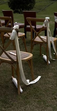 chairs with bows tied to them sitting in the grass