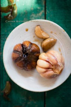 two peeled figs in a white bowl on a green table