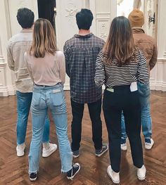 four people standing in a room looking at something