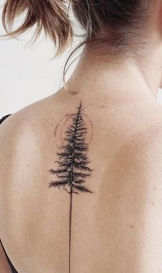 the back of a woman's neck with a tree tattoo on it