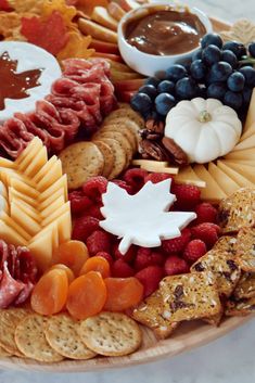 an assortment of cheeses, crackers, and meats on a platter