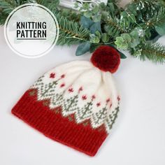 a red and white knitted hat sitting on top of a table next to a christmas tree