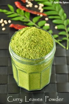 a jar filled with green powder sitting on top of a table next to some leaves