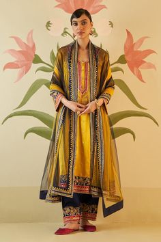 Mustard yellow choga embroidered with midnight blue applique embroidered with mirror work encrusted with tonal silken threads and rose gold kasab. Comes with midnight blue embroidered hem pant and dupatta.
Components: 3
Pattern: Embroidered
Type Of Work: Appliques, mirror, silken thread and kasab work
Neckline: V Neck
Sleeve Type: Three Quarter
Fabric: Silk, Lining: Crepe
Color: Yellow
Other Details: 
Floral patter work
Note: All the jewellery worn by the model is for styling purpose only
Occasi Salwar Pattern, Embroidered Hem, Yellow Silk, How To Hem Pants, Pakistani Dress Design, Types Of Work, Suit Designs, Mirror Work, Fabric Silk