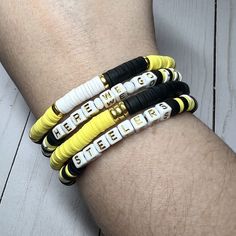 "Cheer on your Pittsburgh Steelers with this Heishi bead bracelet.  Created with gold-toned accent beads and square letter beads. Stretch bracelet measures about 7.25\" NOTE: The best way to keep a stretch bracelet in good shape is to roll the bracelet on and off your hand and wrist. Continuously pulling it wider to put on your wrist will lead to overstretching and possibly breakage.  NOTE: Gold beads may tarnish with prolonged exposure to lotions or perfumes. Not recommended to wear in salt or Casual Gold Heishi Beads Stretch Bracelet, Yellow Heishi Beads Bracelets With Letter Beads, Yellow Heishi Bracelets With Letter Beads, Gold Heishi Beads Bracelet With Letter Beads, Adjustable Yellow Name Bracelet With Letter Beads, Steelers Bracelet, Heishi Bead Bracelet, Football Jewelry, Heishi Bracelet