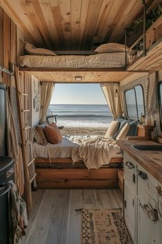 the interior of an rv with a bed, sink and window looking out at the ocean