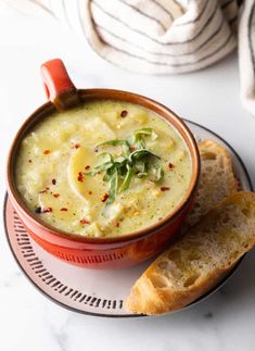 a bowl of soup on a plate with bread