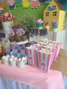 a table topped with lots of cupcakes and cake next to a wall covered in peppa pig decorations