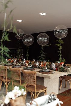 a long table with plates and silverware on it is surrounded by hanging glass orbs