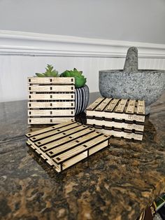 three wooden crates sitting on top of a table next to a vase and planter