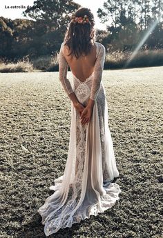 a woman in a white dress is standing in the grass with her back to the camera