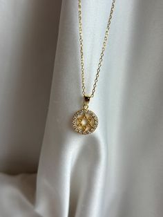 Round and dainty, our Star of David necklace is a must have! Information: ✨Sterling Silver (925 stamped) | 14K Gold Plated ✨High quality AAA+ Cubic Zirconia gemstones ✨Adjustable length: 16" - 18" ✨Hypoallergenic ✨Tarnish resistant A minimalist perfection, our Star of David charm necklace is perfect for those that want a smaller design. The necklace is made with great craftsmanship and attention to detail from the metals to the gemstones. At the center of the charm is the Star of David, surrounded by a CZ gemstone halo design. The charm measures 0.45" by 0.45". The necklace is adjustable from 16" to 18", allowing you to find the perfect fit and create multiple layering styles. This makes a great gift. Round Star, Star Of David Necklace, Jewish Star, Layered Fashion, Diamond Star, Necklace Dainty, Star Of David, Star Charms, Star Necklace