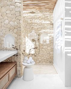 a white bathroom with stone walls and floor