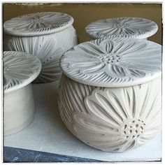 three white vases sitting next to each other on a table