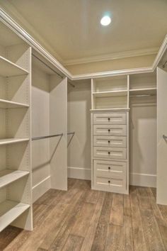 an empty walk in closet with wooden floors and white shelving units on the walls