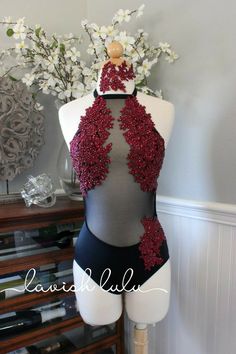 a mannequin with red and black bodysuit on display in front of flowers