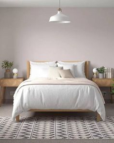 a white bed sitting next to a wooden dresser and table in a room with pink walls