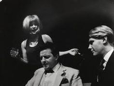 an old black and white photo of a man sitting at a table with two women standing behind him