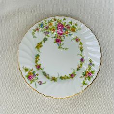 a white plate with flowers on it sitting on a cloth covered tableclothed surface