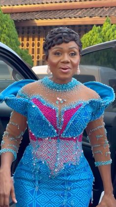 a woman in a blue dress standing next to a car