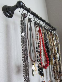 there are many bracelets hanging on the wall next to a lamp shade and curtain rod