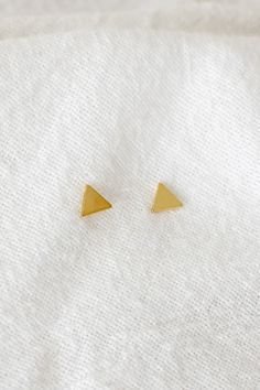 14k gold filled 4mm triangle studs Please note that due to the handmade nature of this piece, they will vary slightly in appearance. There may also be slight color variations from soldering where the post meets the earrings, which is totally normal! Sold as a pair and comes with backings Gold filled is a soft metal so when putting the backings on and taking them off, hold the base of the post to avoid any bending Please note: all earrings are final sale Everyday Gold Triangle Earrings, Gold Triangle Minimalist Earrings, Minimalist Gold Triangle Earrings, Gold Triangle Earring, Gold Triangle Stud Earrings, Minimalist Triangle Brass Jewelry, Trillion Earrings, Triangle Gold Metal Earrings, Triangle Studs