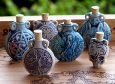 six ceramic vases with designs on them sitting on a wooden table next to each other