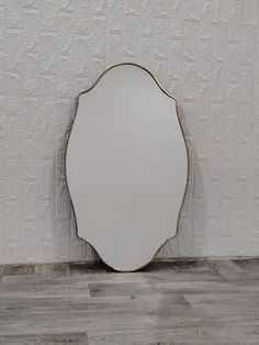 a white mirror sitting on top of a wooden floor next to a wall with a plant