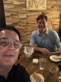 two men sitting at a table with plates of food