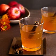 two glasses filled with apple cider on top of a table