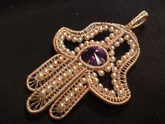 a brooch with pearls and a purple stone in the center on a black background