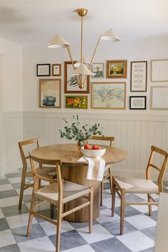 a dining room table with four chairs and pictures on the wall above it, along with an area rug