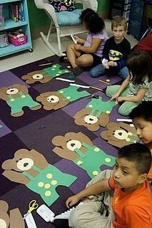 several children sitting on the floor playing with teddy bear rugs and paper cutouts