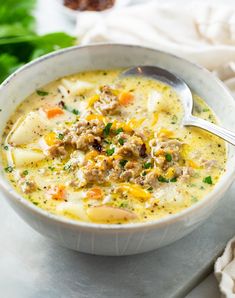 a white bowl filled with soup on top of a table next to a napkin and spoon