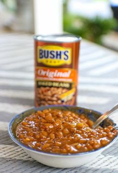 a bowl of baked beans next to a can of bush's