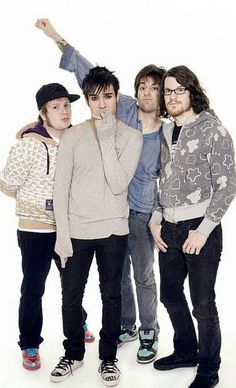 four young men posing for the camera with one pointing at something in front of them