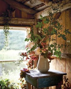 a vase filled with flowers sitting on top of a wooden table next to a window