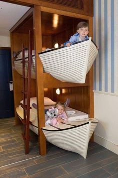 two children are sitting on bunk beds in a room with striped walls and wood flooring