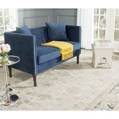 a blue couch with yellow throw pillows on it and a side table in the corner