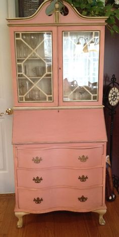 an old pink china cabinet with glass doors and drawers in the front, sitting on top of a hard wood floor