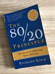 the 80 / 20 principle by richard koch on top of a wooden table with a pen