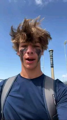 a young man with his face painted like a baseball player is holding a bat and posing for the camera