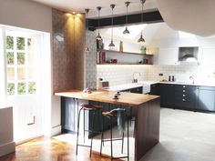 a kitchen with two stools next to an island in the middle of the room