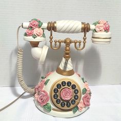 an old fashioned phone with roses painted on the front and sides, sitting on a white surface